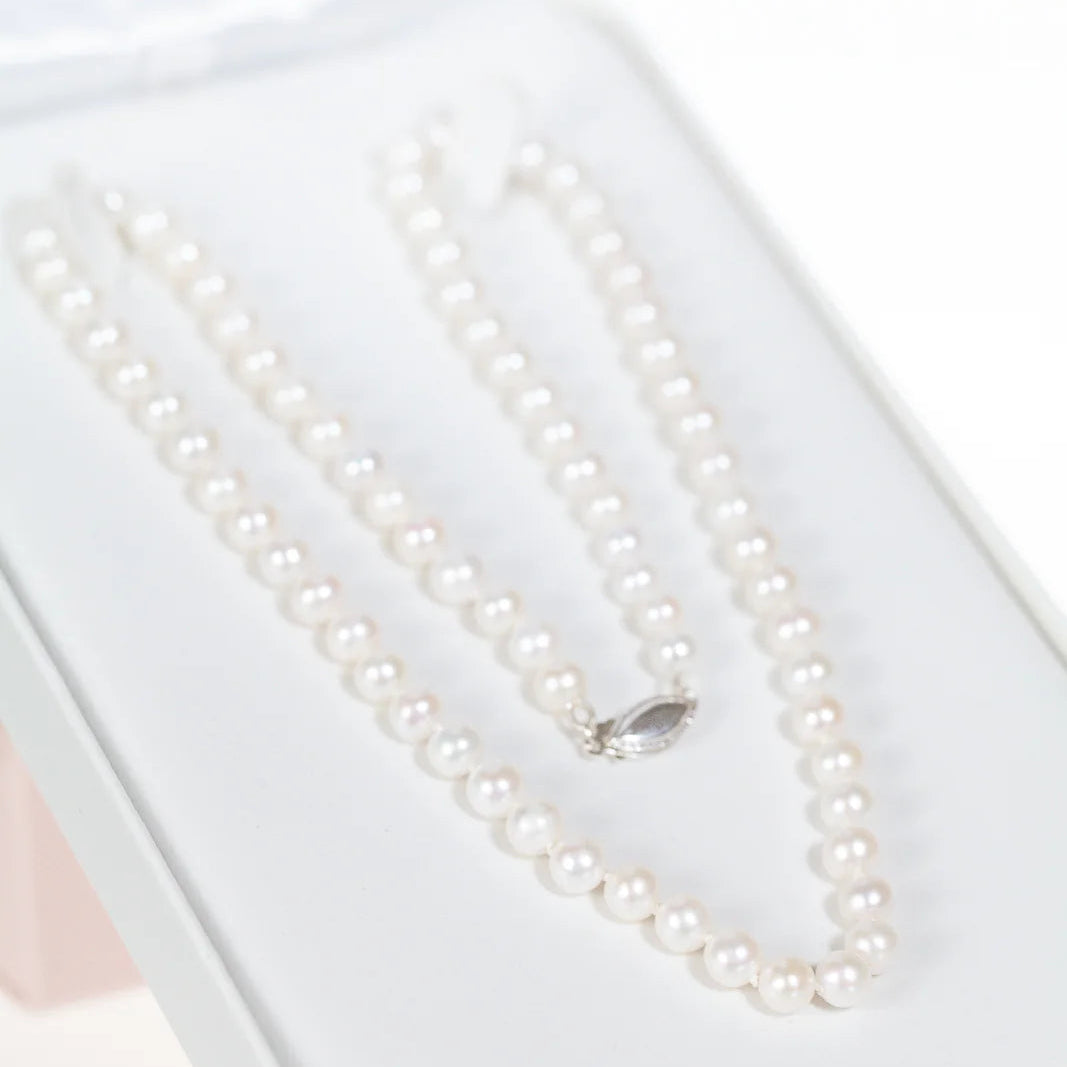 Pearl necklace on a white display box with a white background