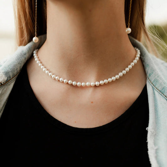 Person wearing a pearl necklace with a blurred background