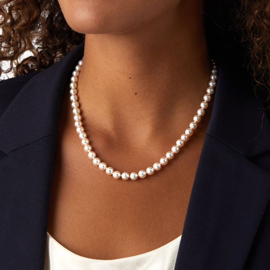 Pearl necklace worn by a person with a dark background
