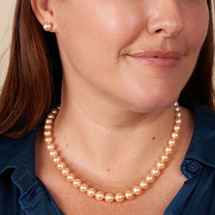 Woman wearing a peach pearl necklace with a close-up of the necklace and part of her face.